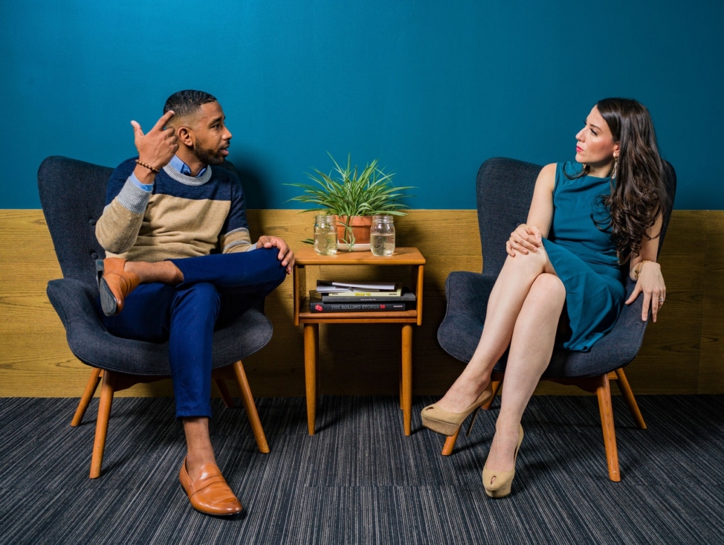 Man & Woman Sitting In Blue Chairs, Having a Discussion