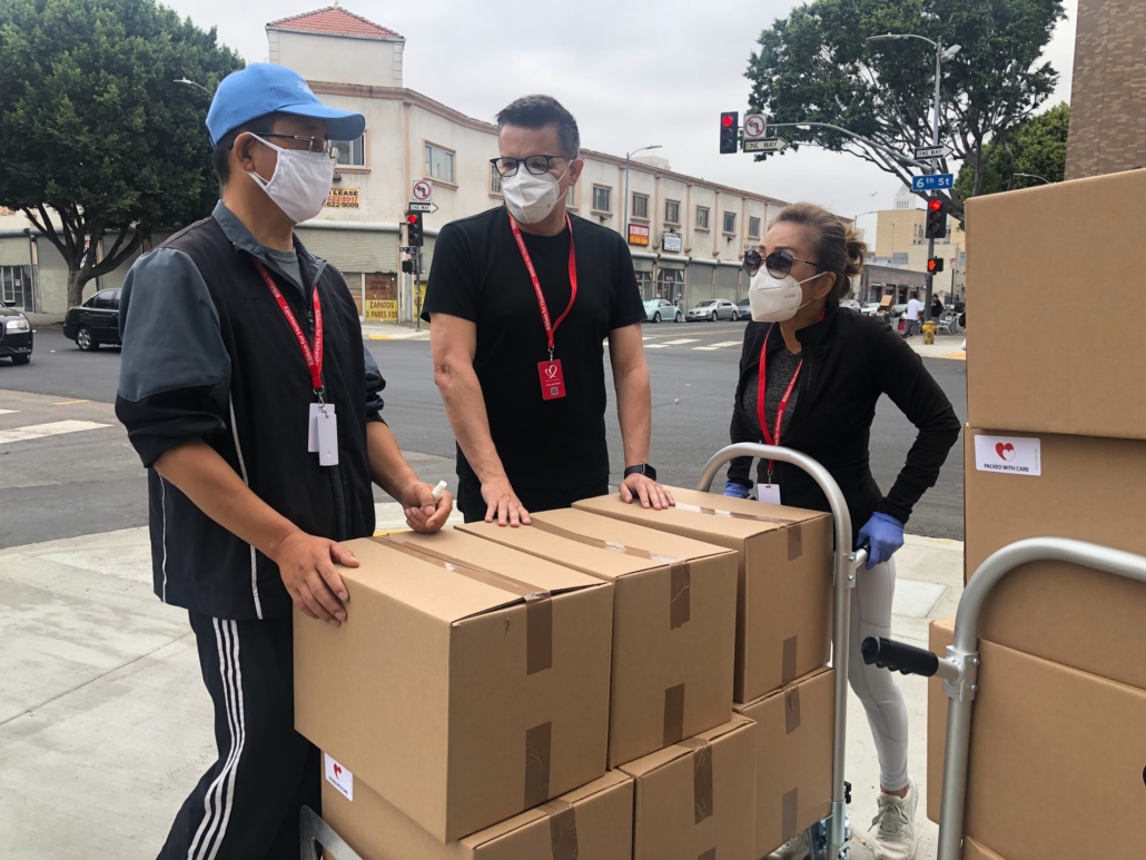 Three people on a street corner delivering boxes