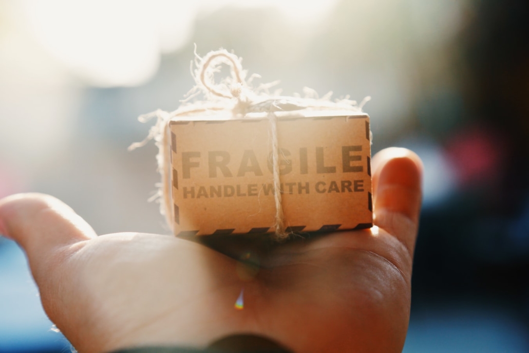A hand holding a small box that says "fragile"