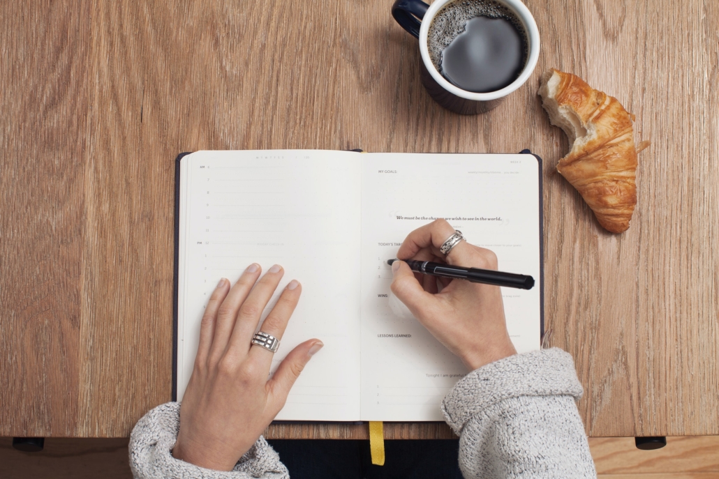 Taking notes, a bitten croissant on the table