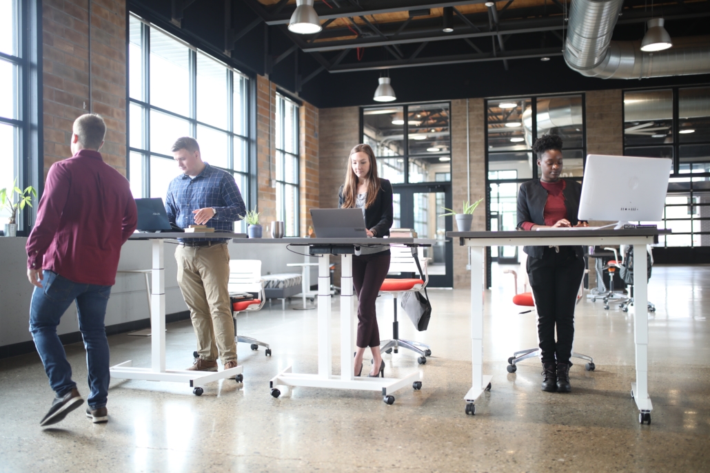 Several workers working at sit-stand desks in a workspace